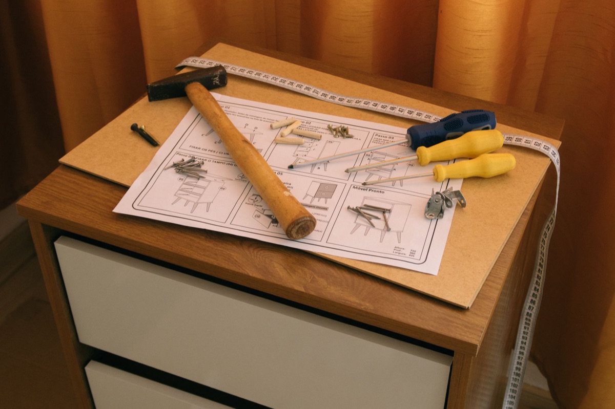 Close-up of essential hand tools including a hammer and screwdrivers on a work surface.