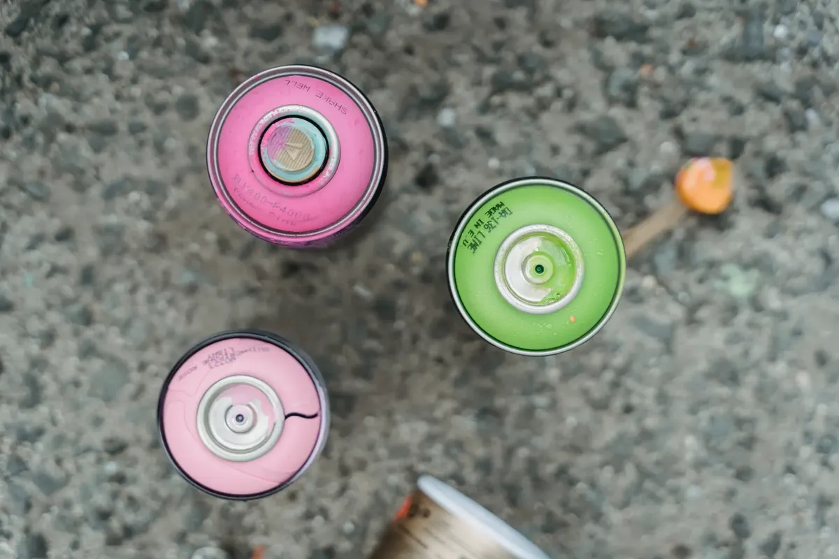 Top view of colorful spray paint cans on concrete surface.