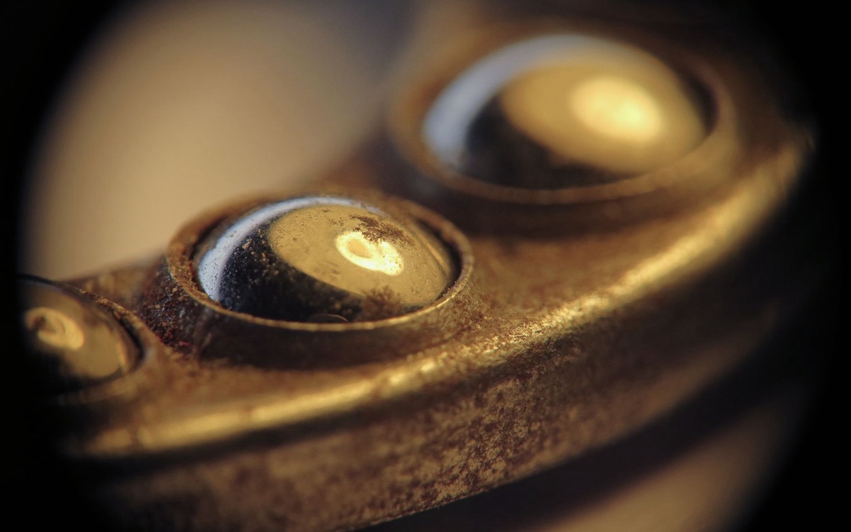 Close-up de um paquímetro analógico sendo usado para medição de precisão em uma peça de metal.