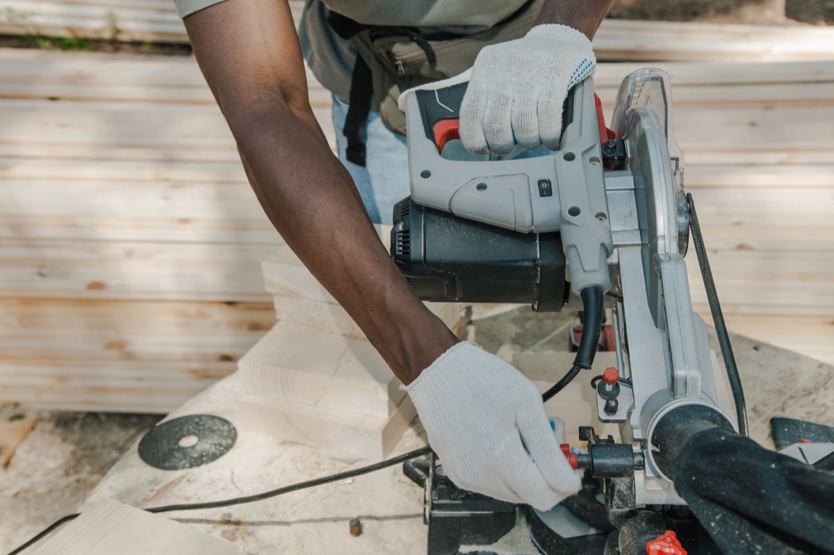 A professional electric circular saw cutting through a thick piece of plywood.