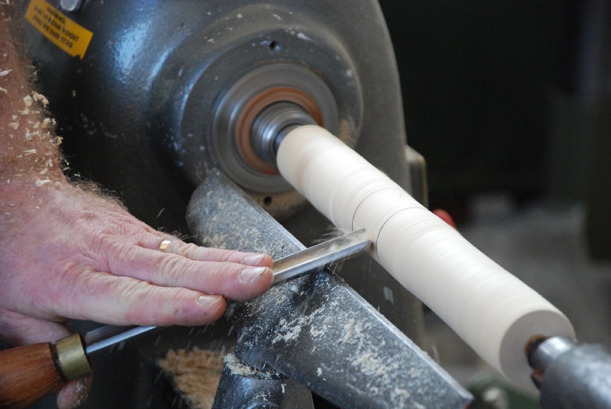 A traditional hand plane tool smoothing the surface of a solid wood plank.