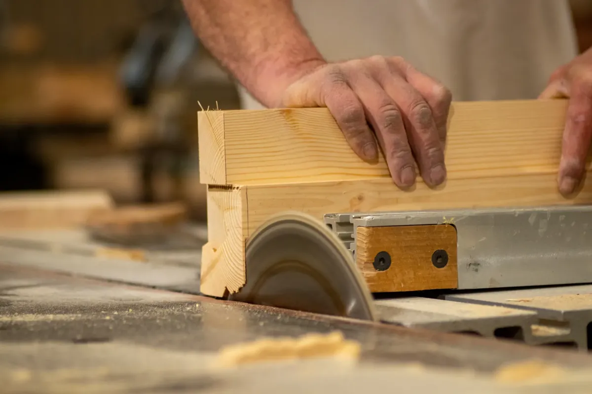 Close-up of a craftsman using a saw, showcasing woodworking skill and precision.