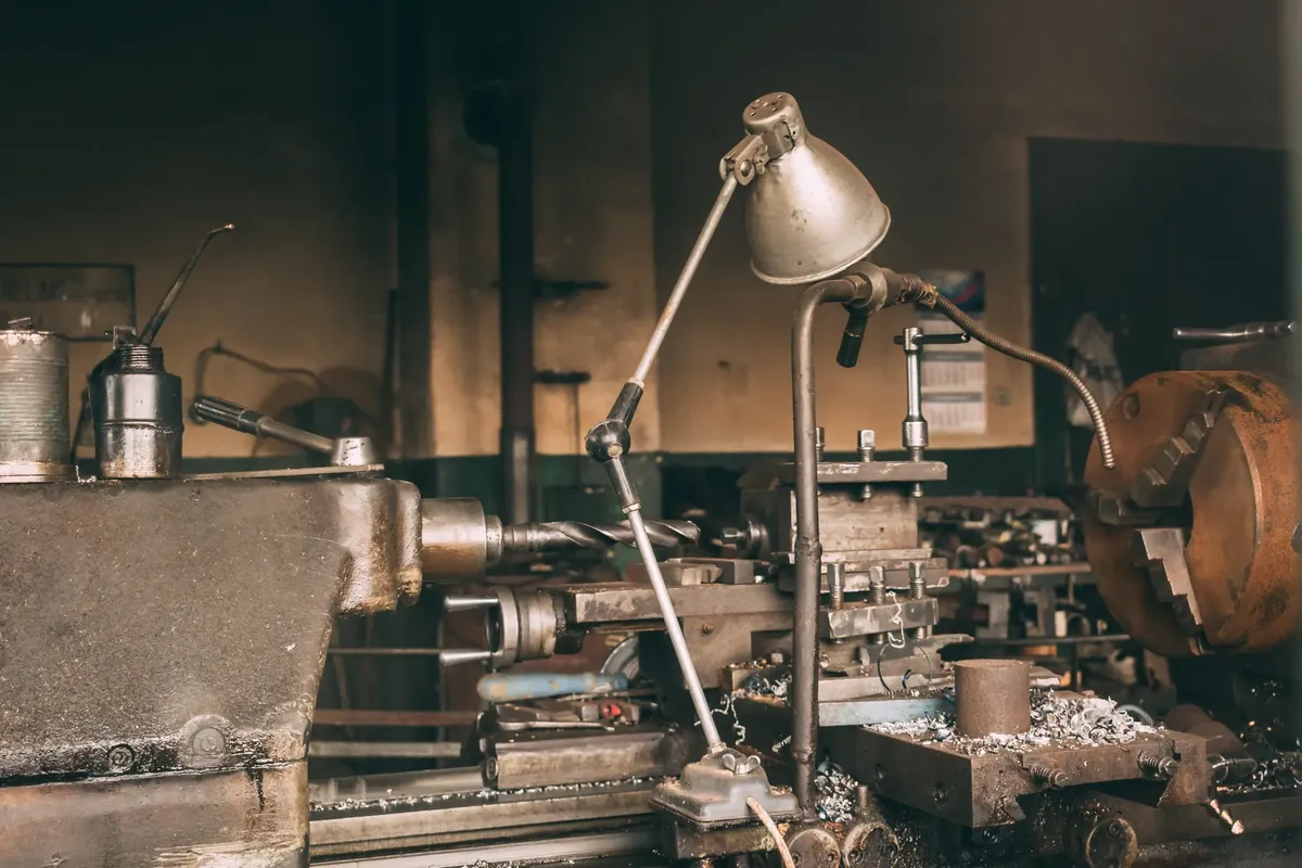 A rusty industrial lathe in a vintage workshop setting showcasing metalwork machinery.