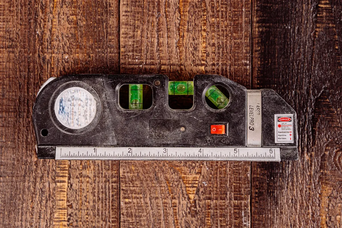 Close-up of a multipurpose laser level tool on a wooden table surface.