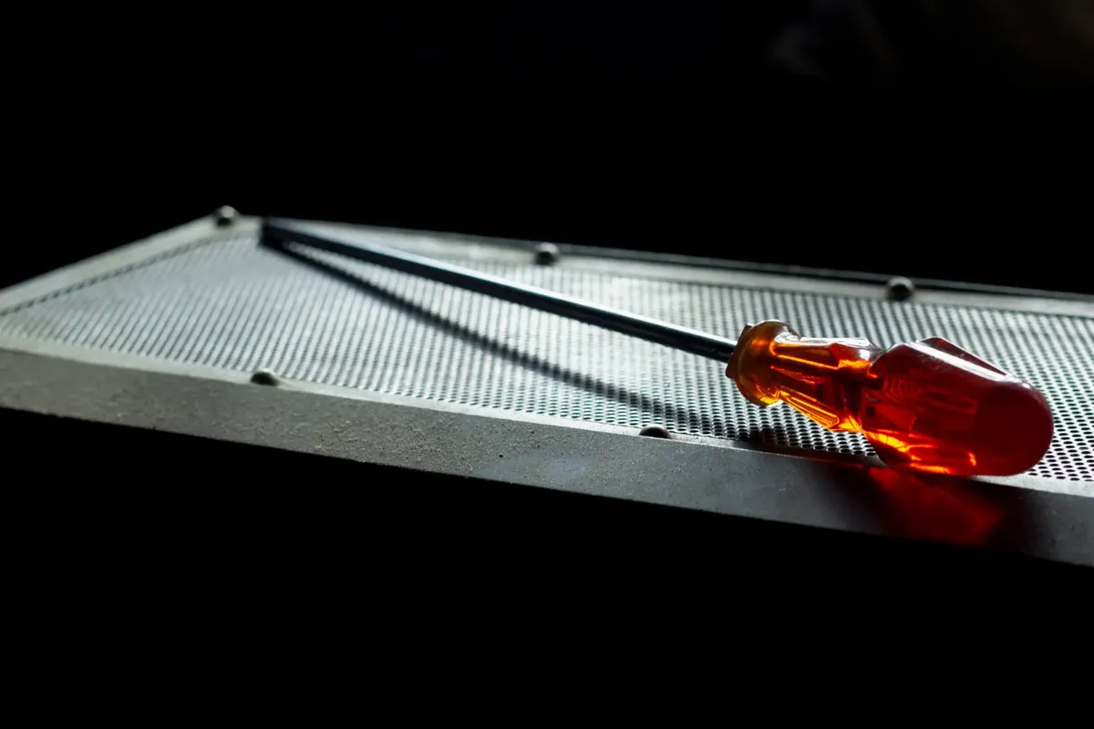 A vivid image showcasing a screwdriver resting on a textured metal plate with dramatic lighting.